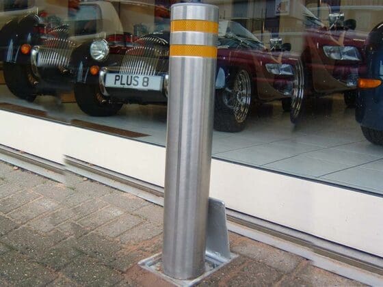 Raised retractable security bollard actively blocking vehicle access for enhanced area protection